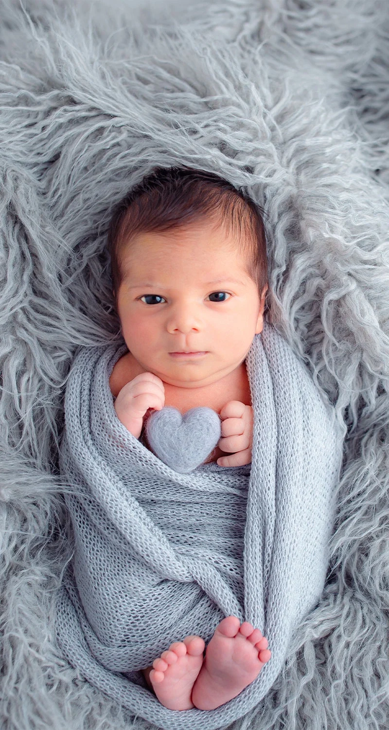 A newborn resting on a soft gray blanket