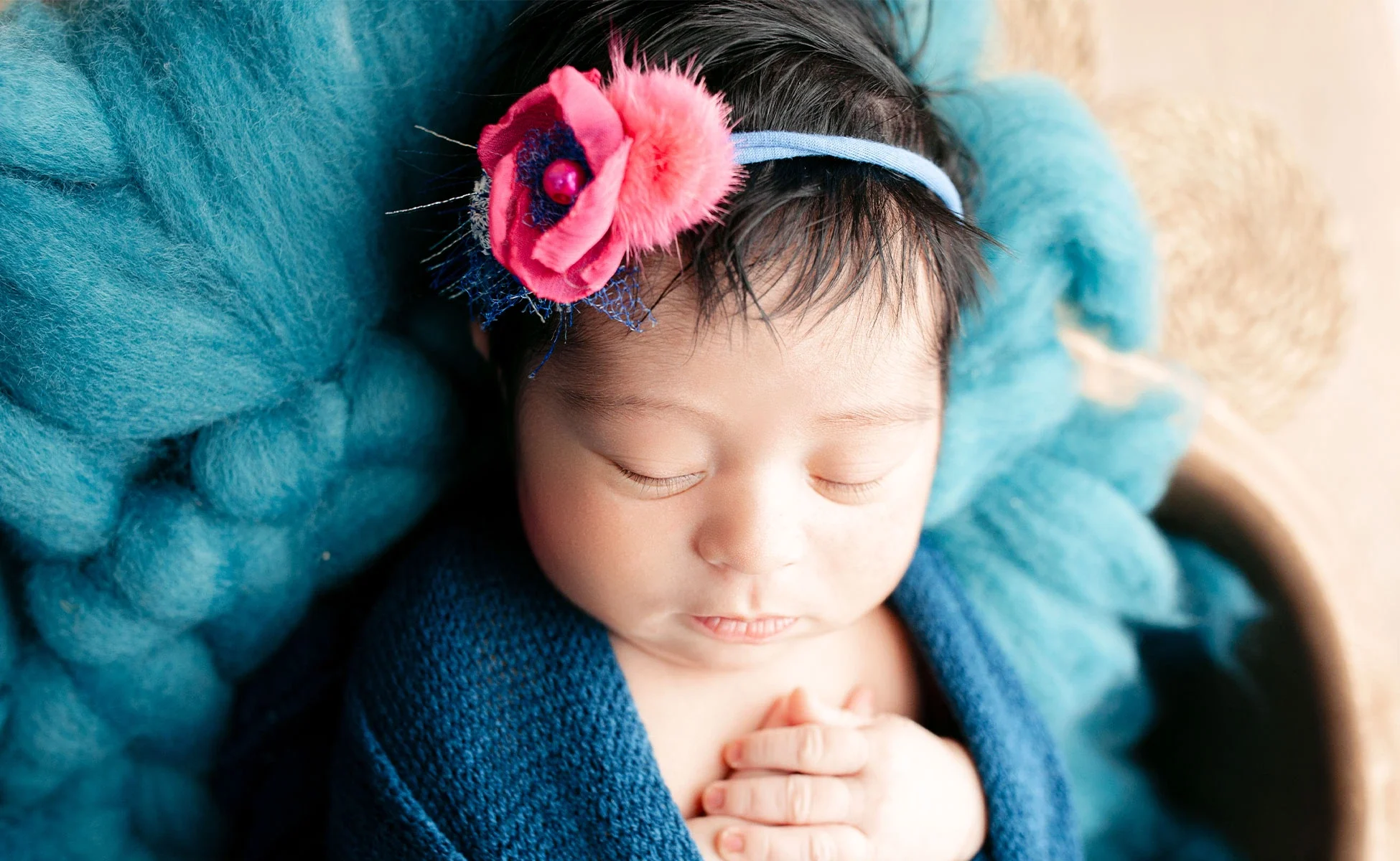 A newborn portrait wrapped in blue and pink fabric